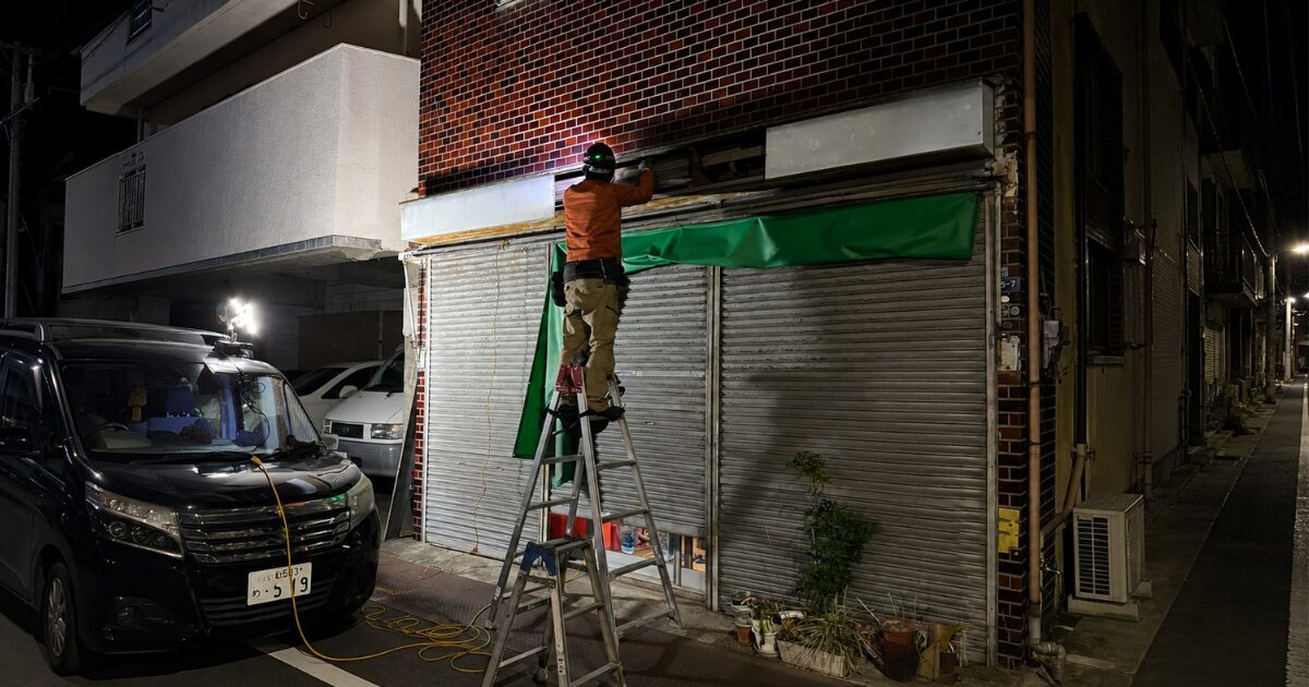 夜間に店舗のシャッターを修理する作業員